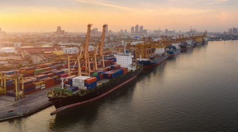 Container ship docked at sea port with a city visible in the background