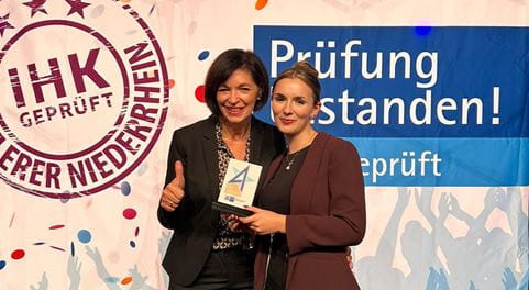 Zwie Frauen, eine von ihnen hält eine Urkunde