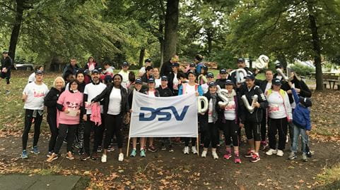 Groupe d'employés DSV en tenue de sport tenant un drapeau DSV