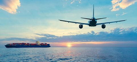Buque navegando en el mar y avión volando durante el atardecer