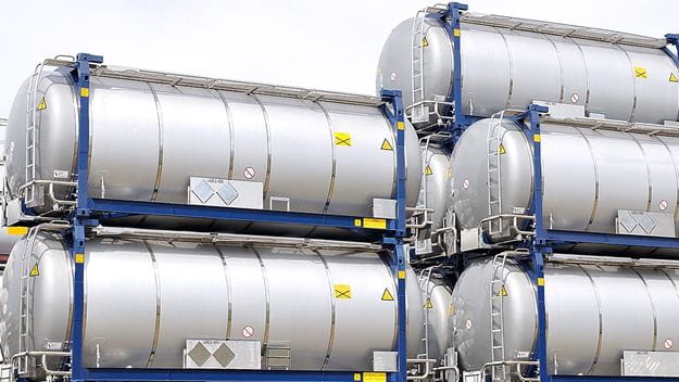 Stacked steel ISO tanks are used to carry bulk goods, liquids, or gases in open yard storage.