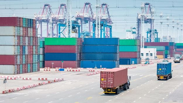 Busy container port with cranes and trucks.