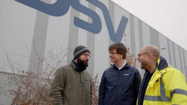 Drei Personen stehen vor DSV Lagerhalle