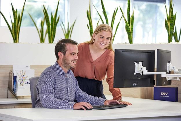 Deux employés de DSV, un homme et une femme regardant un écran d'ordinateur dans un bureau