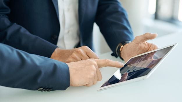 zbliżenie na dłonie pracowników przy tablecie