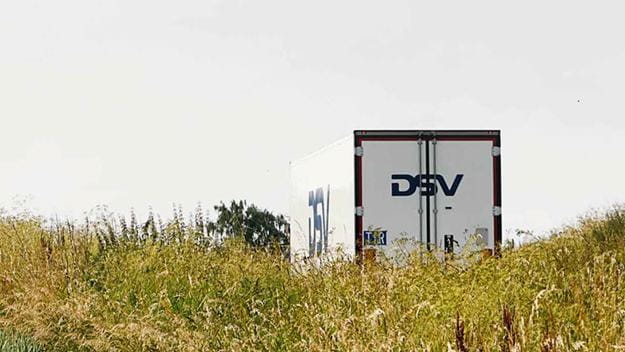 DSV truck driving on a road next to a field