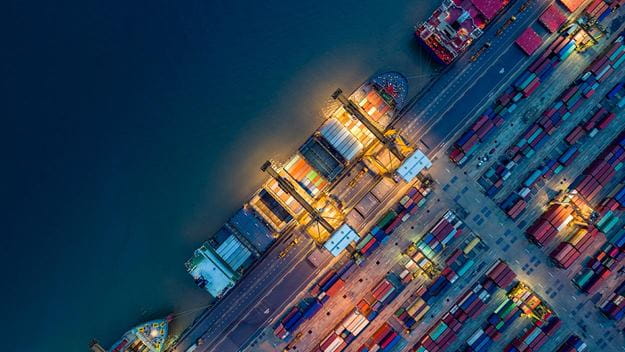 Logistik och transport med containerfartyg och lastplan med fungerande kranbro på varvet vid soluppgången, logistisk importexport och transportindustribakgrund.