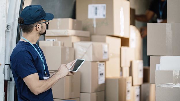 Modern leverans - Förare som använder mobiltelefon för att hantera paket i en lastbil.