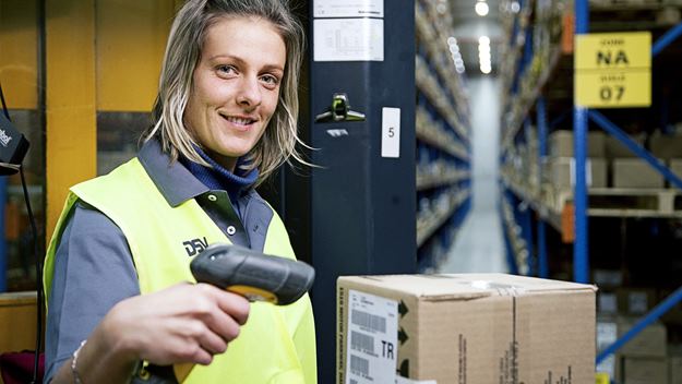 Warehouse worker scanning barcode on package with manual device