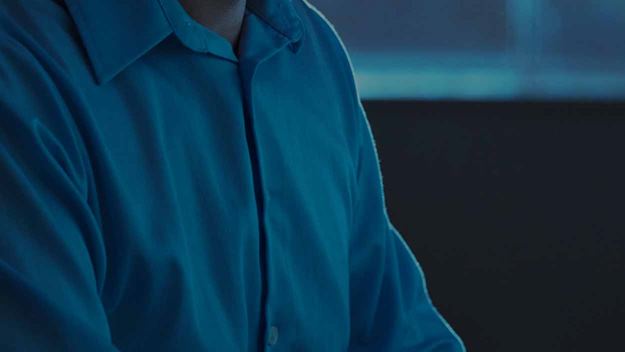 A man wearing a headset working at his desk in an office environment. One image is split into 6 separate images showing a part of the image