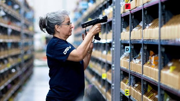 Warehouse worker using scanning device at pick racks