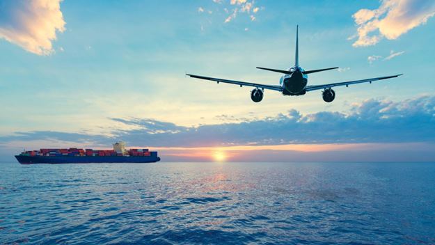 Avión y barco de carga volando y navegando en el mar durante el atardecer.