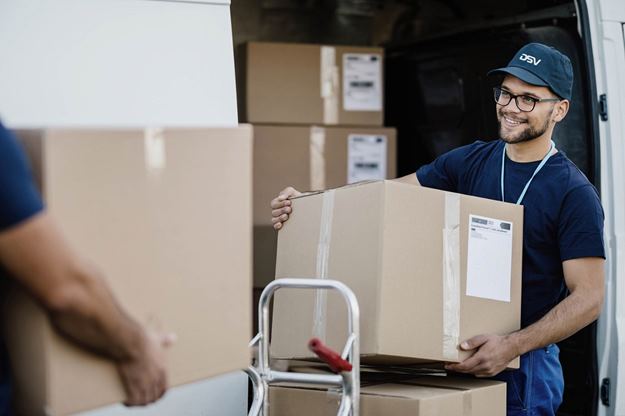 Man delivering boxes while wearing DSV blue shirt and cap smiling