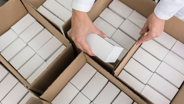 Supply chain packaging: Hands carefully packing products for transport.