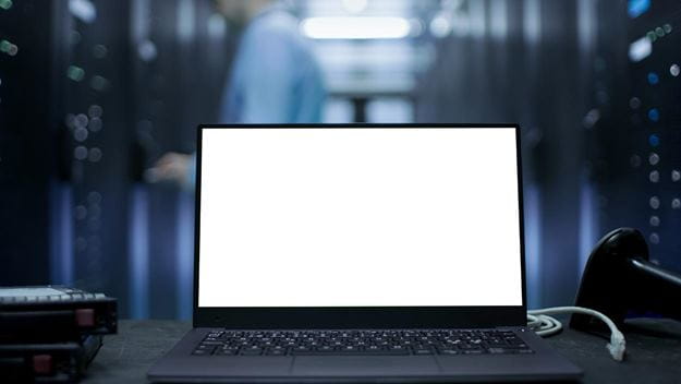 Laptop with blank screen in a server room with racks in the background.
